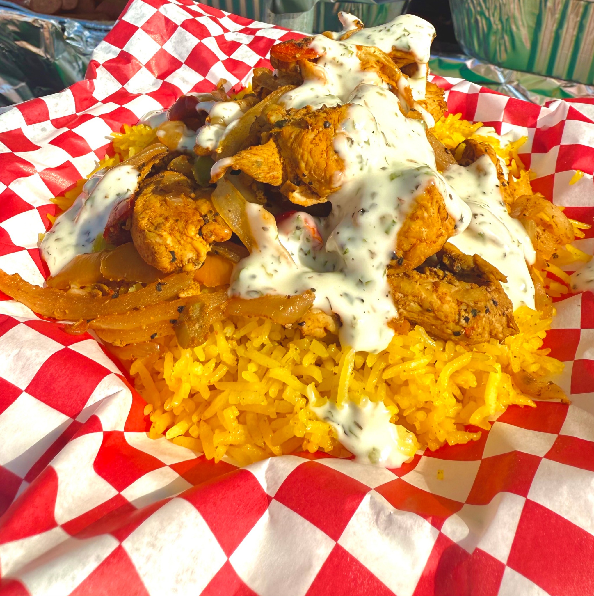 Chicken over rice topped with white sauce